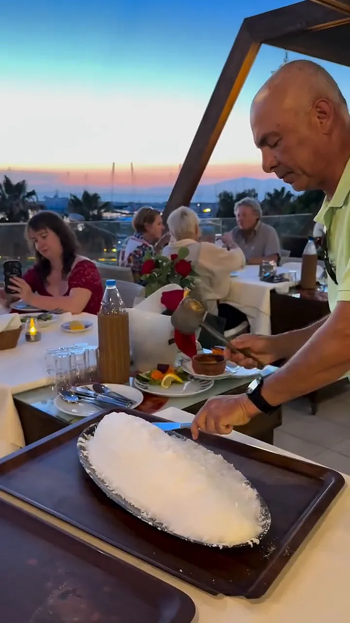 Video: on the terrace at dusk, salt-crusted fish being cracked open with a mallet at the table
